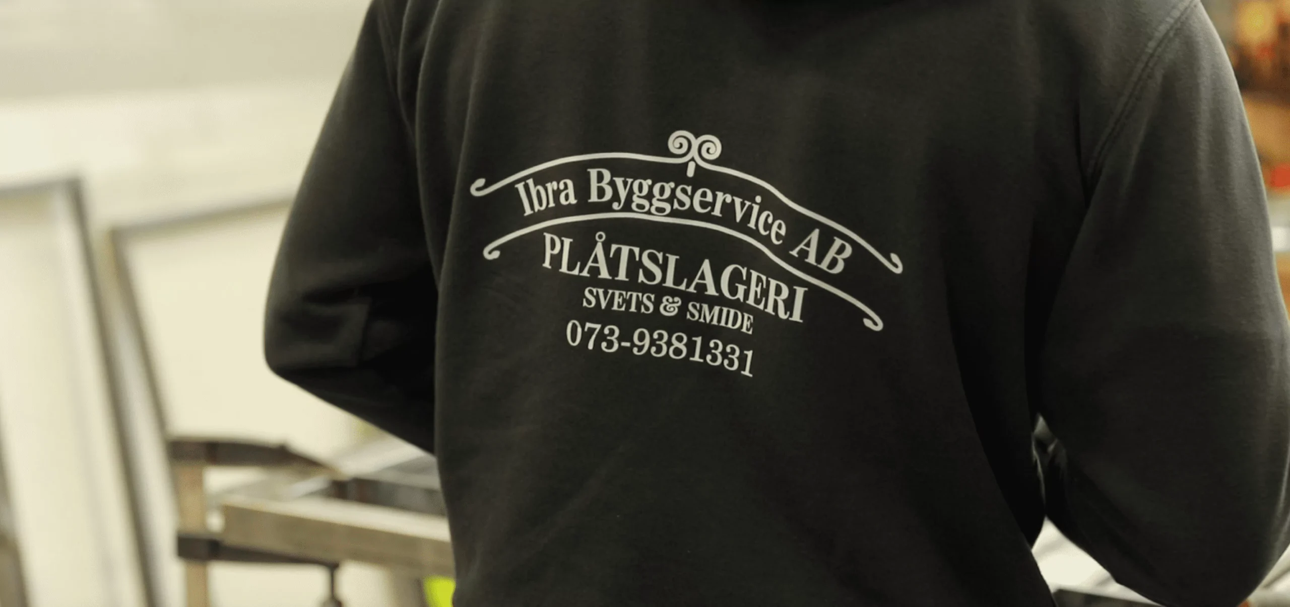 Baksidan av en svart hoodie med vit text Ibra Byggservice AB PLÅTSLAGERI SVETS & SMIDE 073-9381331
